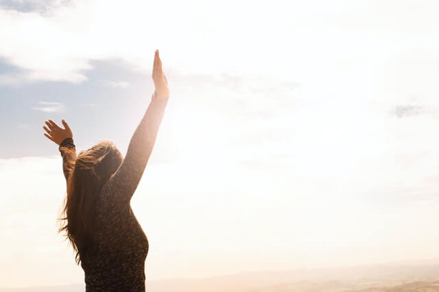 woman-outside-raising-arms-to-the-sky