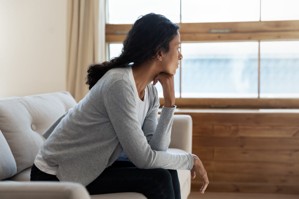 Thoughtful woman sitting at the couch