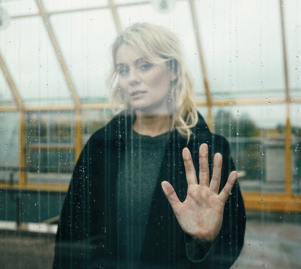 woman holding hand against glass wall